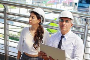 Man and woman engineers inspect the site  outdoor construction projects in the modern downtown area Engineers wear white safety helmets for safety photo