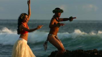 Polynesian dancers perform by ocean, slow motion video