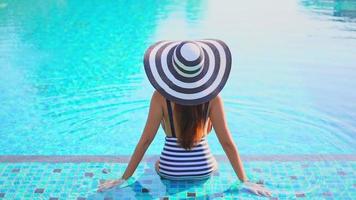 Mujer asiática relajarse y disfrutar de la piscina al aire libre