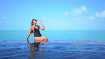 Mujer asiática relajarse y disfrutar de la piscina al aire libre video