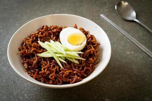 fideos instantáneos coreanos con salsa de frijoles negros cubiertos con pepino y huevo duro, jjajangmyeon - estilo de comida coreana foto