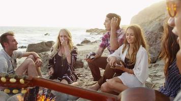 Group of young people hanging out at beach around campfire video