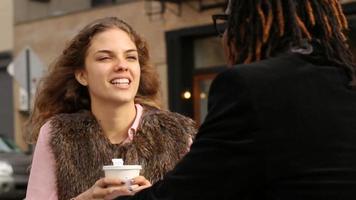 jovem casal sentado em um café ao ar livre conversando video