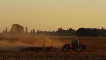 champ de labour du tracteur au coucher du soleil. video