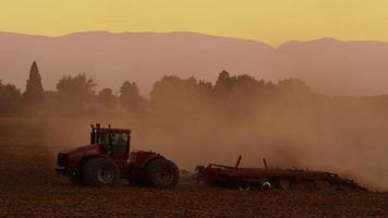 champ de labour du tracteur au coucher du soleil.