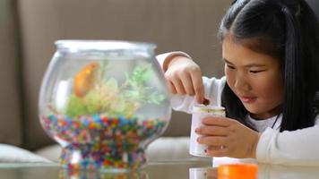 Young girl feeding pet goldfish video