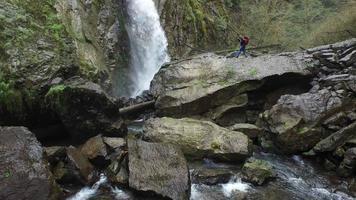 Backpacker walking up rocks to waterfall video