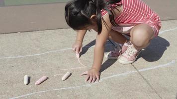 junges Mädchen spielt Himmel und Hölle im Park und zeichnet mit Kreide video