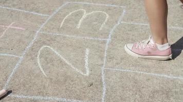 Niña jugando a la rayuela en el parque, primer plano de los pies video