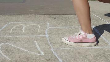 Niña jugando a la rayuela en el parque, primer plano de los pies video