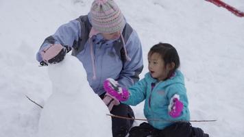 Mutter und Tochter bauen gemeinsam Schneemann video