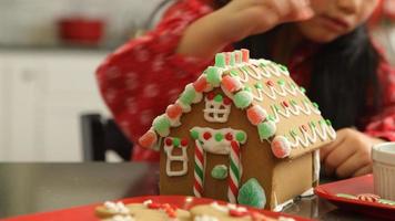 Nahaufnahme eines jungen Mädchens, das Lebkuchenhaus zu Weihnachten dekoriert? video