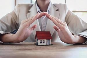 Woman hand protecting a house under hands photo