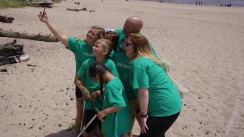 voluntarios tomando fotos juntos en la limpieza de la playa video