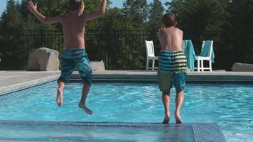 två pojkar hoppar i poolen i super slow motion video