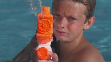 Closeup of boy spraying water gun in super slow motion video