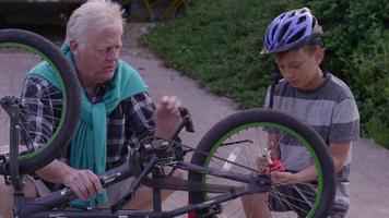 äldre man och barnbarn fixar cykel tillsammans video