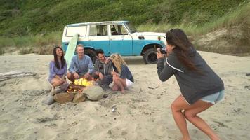 Grupo de amigos en la playa pasando el rato junto a la fogata tomando fotos video
