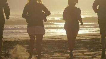 grupp vänner springer till havet vid solnedgången i ultrarapid video