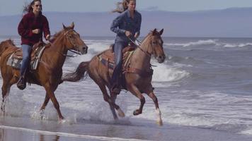 mulheres andando a cavalo na praia em câmera lenta video