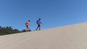 coppia che fa un'escursione sulle dune di sabbia in spiaggia video