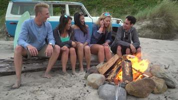 Group of friends at beach hanging out by campfire