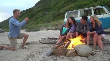 groep vrienden op het strand rondhangen bij het kampvuur video