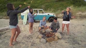 gruppo di amici in spiaggia che passano il tempo davanti al fuoco e giocano con le stelle filanti video