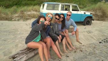 Grupo de amigos en la playa pasando el rato junto a la fogata tomando selfie video