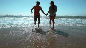 Couple at beach running into surf in super slow motion video