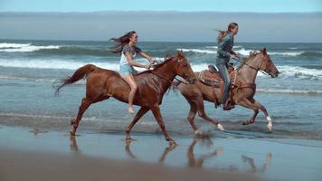 Disparo de cámara super lenta de mujeres a caballo en la playa, oregon, rodada en phantom flex 4k video