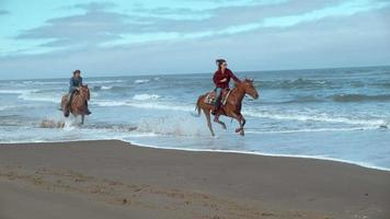 Disparo de cámara super lenta de mujeres a caballo en la playa, oregon, rodada en phantom flex 4k video