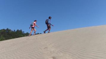 coppia che fa un'escursione sulle dune di sabbia in spiaggia video