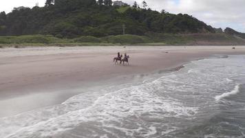 Luftaufnahme von Frauen, die Pferde am Strand reiten