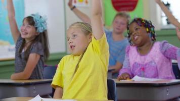 Students raise hands in school classroom video