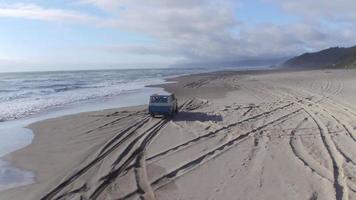 luchtfoto van een groep vrienden die in een vintage voertuig op het strand rijden video