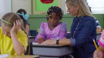 Teacher helps student with writing project in school classroom video