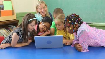 Teacher and students work on laptop computer in school classroom video