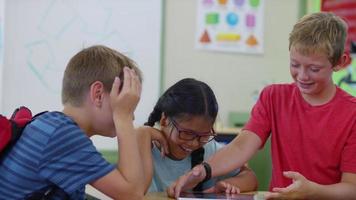 Three students having fun playing on digital tablet video