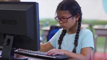 Young girl in school classroom working on computer video