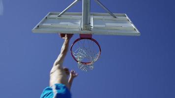 Tiro de cámara lenta de ángulo bajo de hombre haciendo bandeja de baloncesto video