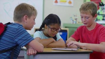 Three students having fun playing on digital tablet video