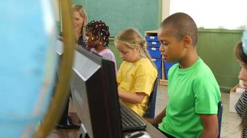 professor e alunos trabalhando em computadores na sala de aula da escola video