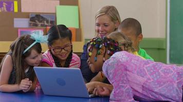 professor e grupo de alunos usam laptop na sala de aula da escola