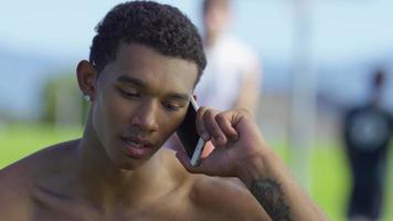 Teen basketball player talking on cell phone at outdoor court video