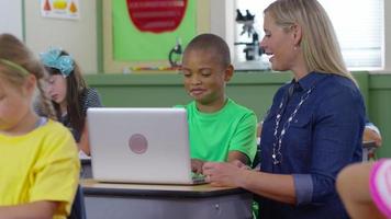 Teacher and student use laptop computer in school classroom video