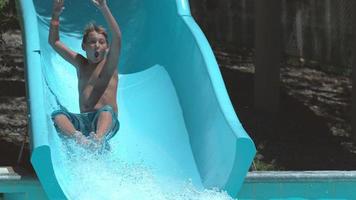 pojke går ner vattenrutschbanan i super slow motion video