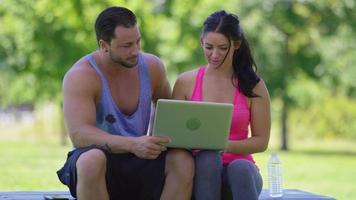 casal atlético no parque usa laptop video
