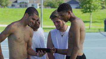 grupo de jogadores adolescentes de basquete olhando para um tablet digital