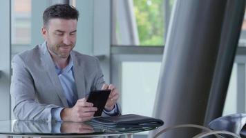 Young businessman using digital tablet in office lobby video